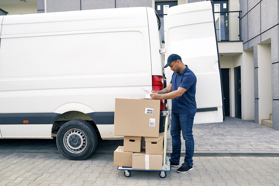 Courier driver organizing packages next to a delivery van, showcasing the efficiency and time-saving benefits of Routary's route optimization for businesses.